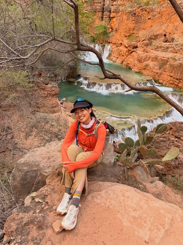 Fuma sitting beside turquoise water and red canyon rock at Havasupai