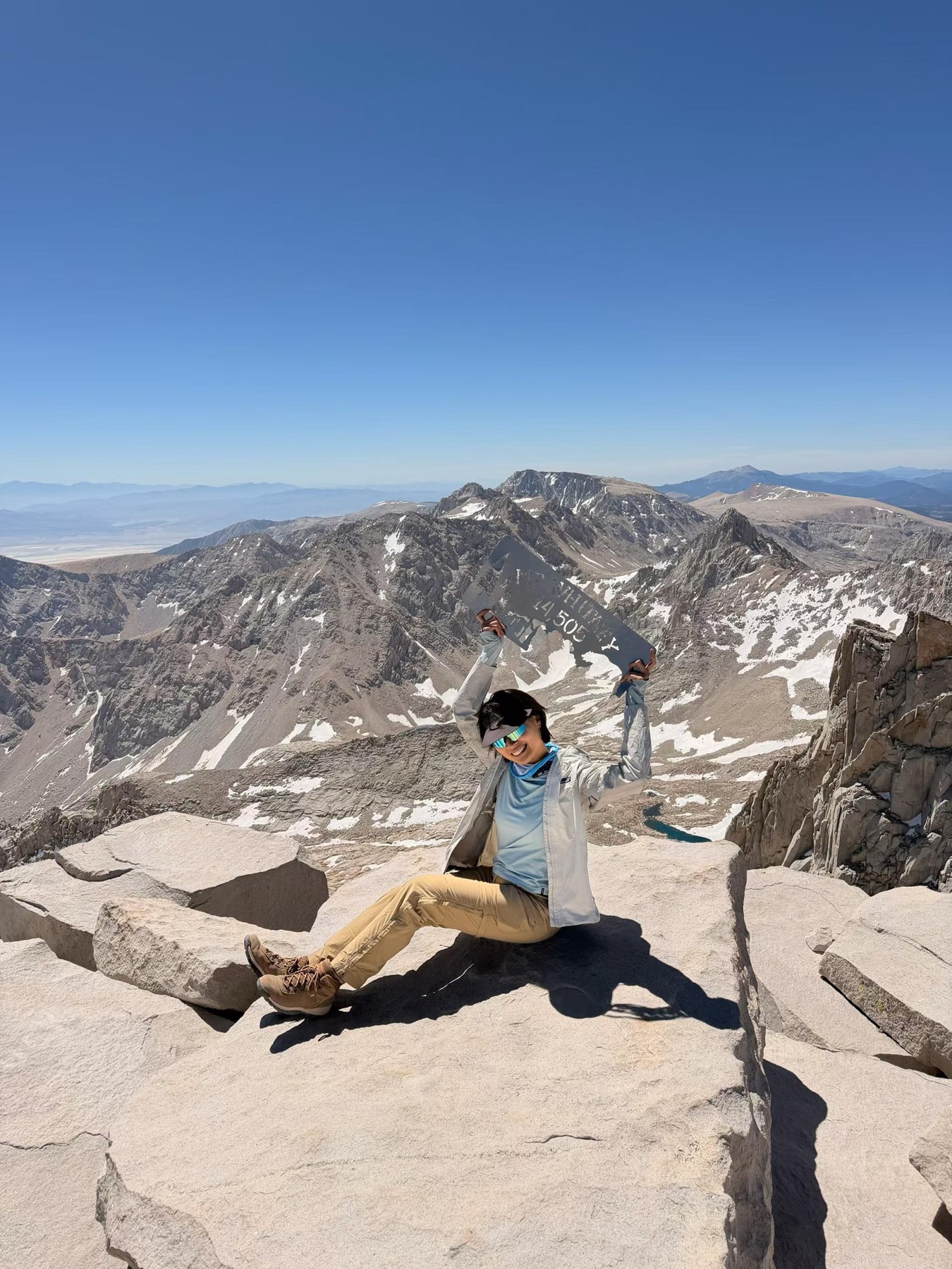 Fuma sitting on the summit of Mt. Whitney with the Sierra Nevada behind her