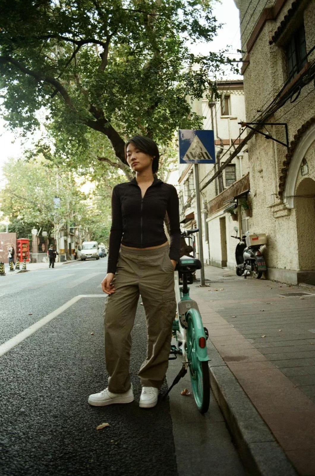 Fuma standing beside a shared bicycle on a Shanghai street